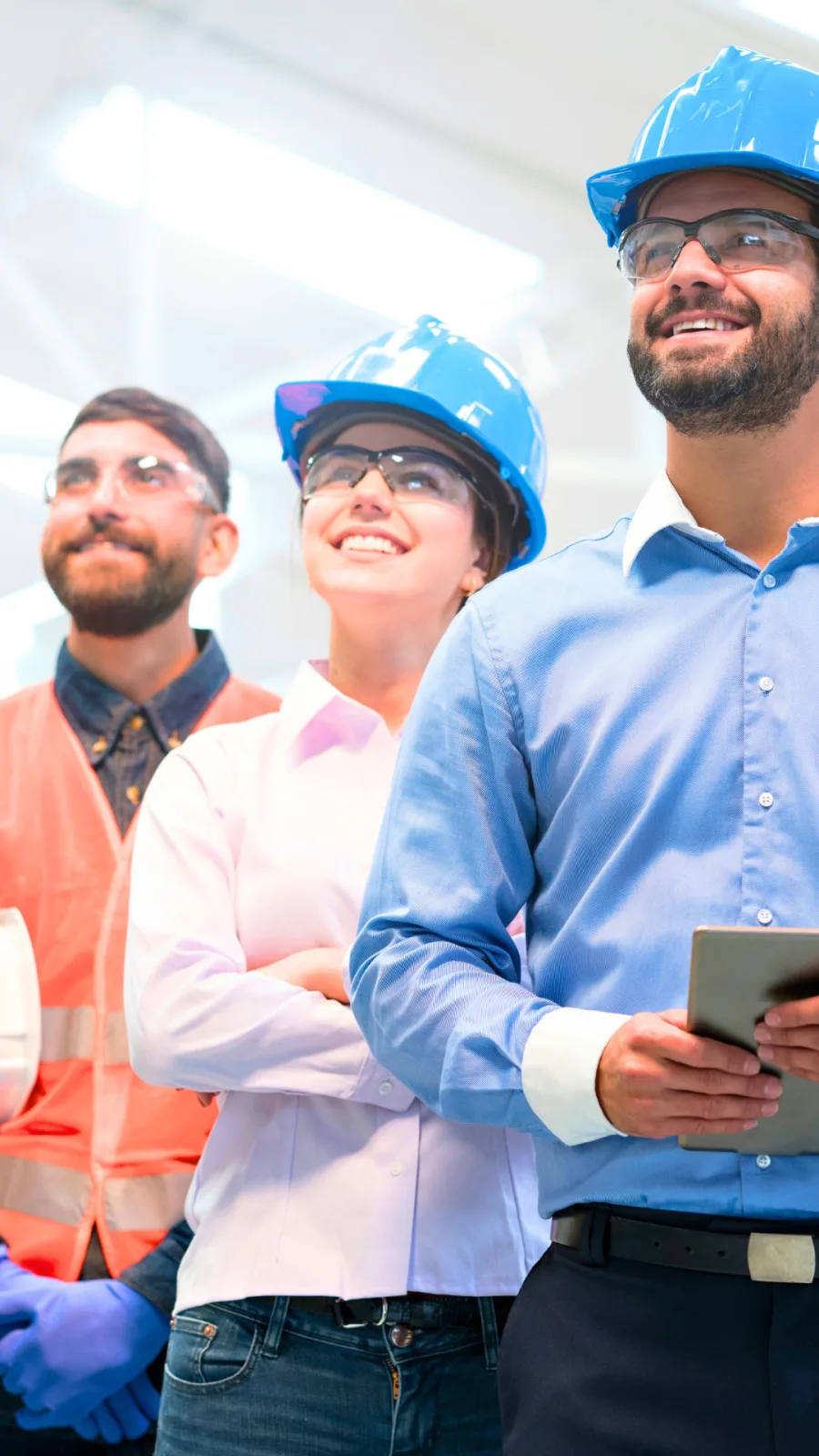Equipe corporativa e operacional em visita a planta industrial, com camisas sociais, colete refletivo, capacetes e óculos de proteção